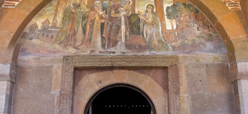 Entrance and tympanum fresco beneath a stone arch at Saint Gayane Church